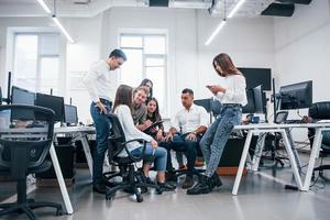 grupo de jóvenes empresarios que están de pie, sentados y trabajando en la oficina foto