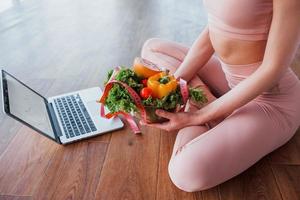 Sportive woman sitting on the table with laptop and healthy food photo