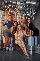 Young women in festive clothes celebrating New Year indoors of christmas decorated room together photo