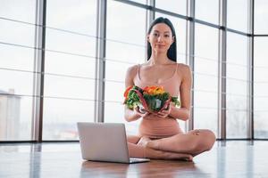 Sportive woman sitting on the table with laptop and healthy food photo