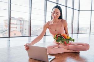 Sportive woman sitting on the table with laptop and healthy food photo