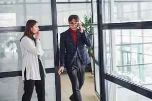 Two office workers in formal clothes indoors have a busy working day photo