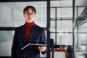 oficinista con gafas y ropa formal de pie en el interior foto