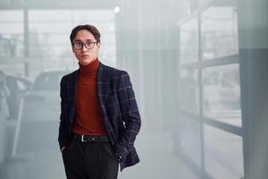 joven hombre de negocios con traje de lujo y ropa formal posando para la cámara en el interior foto