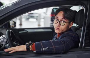 Man in eyewear and formal clothes sitting inside of modern car photo