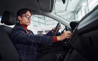 Man in eyewear and formal clothes sitting inside of modern car photo