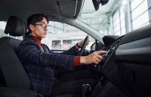 Man in eyewear and formal clothes sitting inside of modern car photo