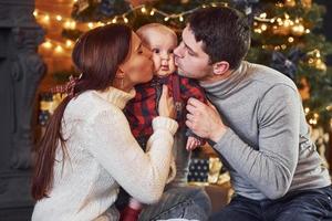 hermosa pareja caucásica celebrando la navidad en el interior con su pequeño hijo foto