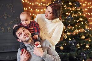 Beautiful caucasian couple celebrating christmas indoors with their little son photo