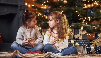 dos niñas se divierten en una habitación decorada con navidad con cajas de regalo foto