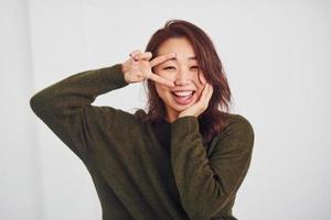 Portrait of happy asian young girl that have fun indoors in the studio against white background photo