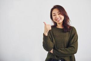 Portrait of happy asian young girl that shows thumb up indoors in the studio against white background photo