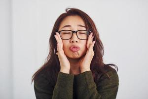 Portrait of happy asian young girl in eyewear that standing indoors in the studio against white background photo