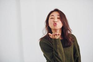 retrato de una joven asiática feliz que está de pie en el interior del estudio con fondo blanco foto