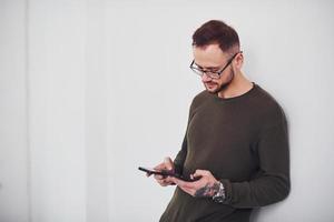 Young guy in sunglasses standing indoors against white background photo