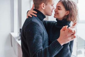 Cute young couple embracing each other indoors near the window photo