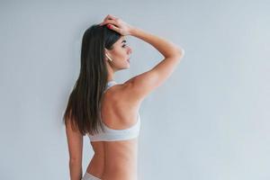 Young beautiful brunette in underwear is indoors in the studio against white background photo