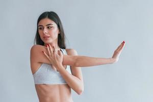 La joven y hermosa morena en ropa interior está en el interior del estudio con fondo blanco. foto