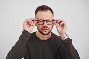 Young guy in sunglasses standing indoors against white background photo