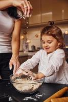 Mother with her little daughter preparing food on kitchen and have fun photo