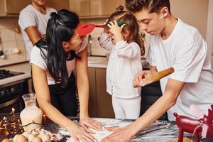 la familia feliz se divierte en la cocina y prepara la comida foto