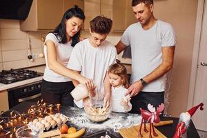 la familia feliz se divierte en la cocina y prepara la comida foto