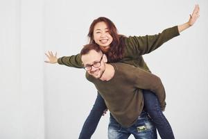 Happy multi ethnic couple in casual clothes have fun together indoors in the studio. Caucasian guy with asian girlfriend photo