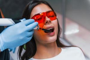 Beautiful woman in red protective glasses have a visit in the dentist clinic. Conception of stomatology photo