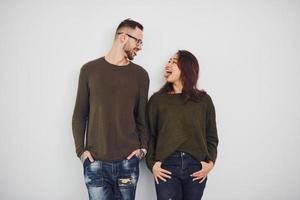 feliz pareja multiétnica con ropa informal está junta en el interior del estudio. chico caucásico con novia asiática foto