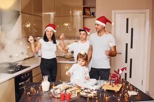 Cheerful family with sparklers in hands celebrating New year together on the kitchen photo