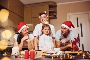 Festive family in christmas hats have fun on the kitchen and preparing food photo
