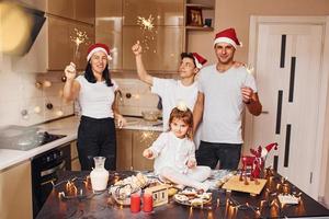 Cheerful family with sparklers in hands celebrating New year together on the kitchen photo