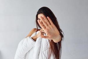 Stop gesture. Woman covering her body by towel in the studio against white background photo