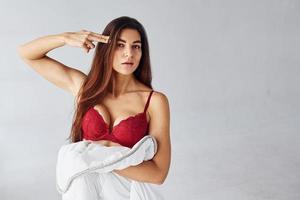 Woman in red underwear covering her body by towel in the studio against white background photo