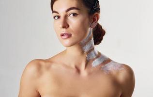 Naked woman with paint on neck is in the studio against white background photo