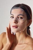 Portrait of woman is in the studio against white background with beauty mask on face photo