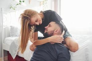 Young married couple kissing each other in bedroom at daytime photo