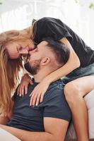 Young married couple kissing each other in bedroom at daytime photo