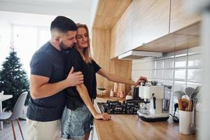 mañana para una pareja casada joven que está de pie en el interior de la cocina foto