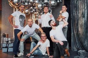 Group of cheerful men standing together in christmas decorated room and posing for a camera photo