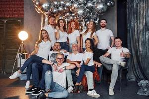 jóvenes positivos sentados y celebrando el año nuevo en una habitación decorada de navidad con globos juntos foto