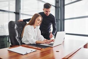 Woman and man in formal clothes working together indoors in the office by table photo