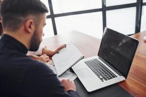 Woman and man in formal clothes working together indoors in the office by table with documents photo