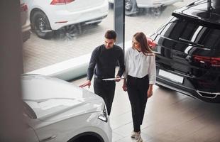 Woman choosing car by help of male assistant indoors in the salon photo