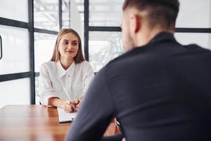 Rear view. Woman and man in formal clothes working together indoors in the office by table photo