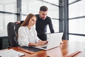 Woman and man in formal clothes working together indoors in the office by table photo