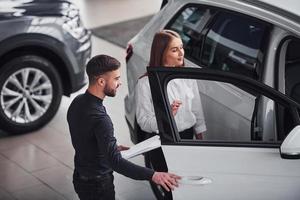 Woman choosing car by help of male assistant indoors in the salon photo