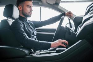 Man in elegant clothes sitting in brand new expencive automobile photo