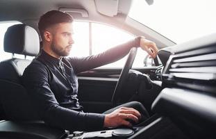 Man in elegant clothes sitting in brand new expencive automobile photo