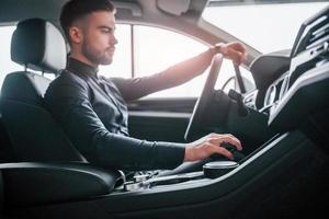 Man in elegant clothes sitting in brand new expencive automobile photo